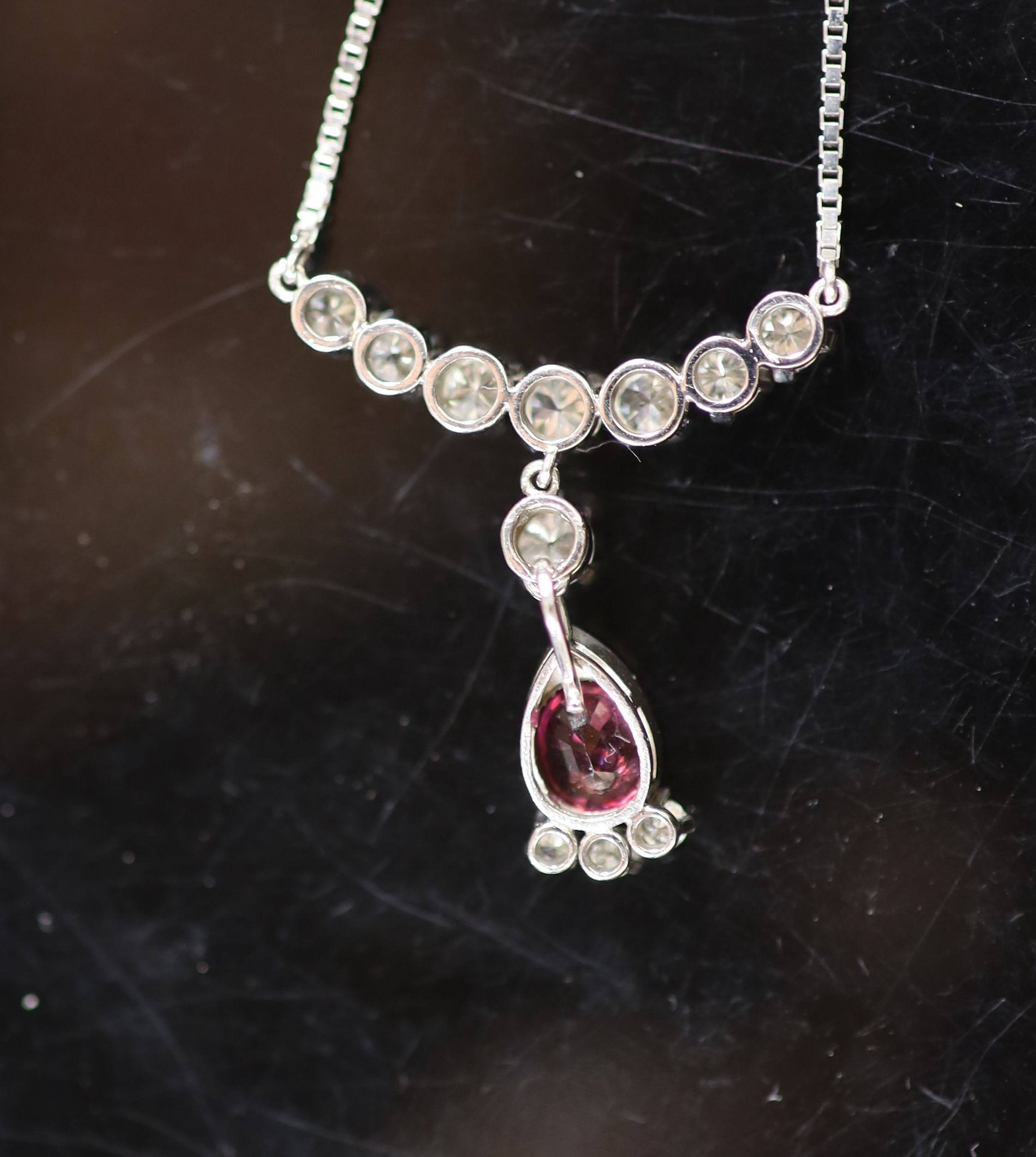 A modern Italian 18ct white gold, single stone oval cut ruby and eleven stone diamond set drop pendant necklace